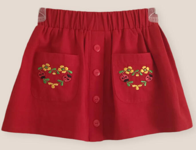 faldita de manta roja con bordado de catarinas y flores en forma de corazon
